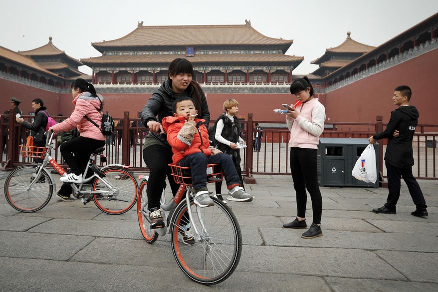 In this Wednesday, March 22, 2017 photo, visitors ride bicycles from bike-sharing company Mobile in Beijing, China. As many as 2.2 million of these two-wheelers have been deployed, which are available for rent for as little as U.S. 7 cents for half an hour, in the latest symbol of heavy spending in China's internet sector where startups are in a race to attract more users to their services. (AP Photo/Andy Wong)