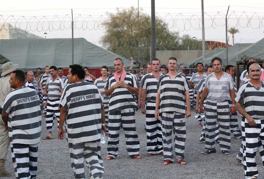 File - In this June 23, 2012, file photo, inmates watch as Maricopa County Sheriff Joe Arpaio gives a tour for church leaders through a Maricopa County Sheriff's Office jail called "Tent City" in Phoenix. Newly elected Maricopa County Sheriff Paul Penzone announced Tuesday, April 4, 2017, that he will be closing the tent city jail in the coming months and relocating inmates to other jails. (AP Photo/Matt York, File)