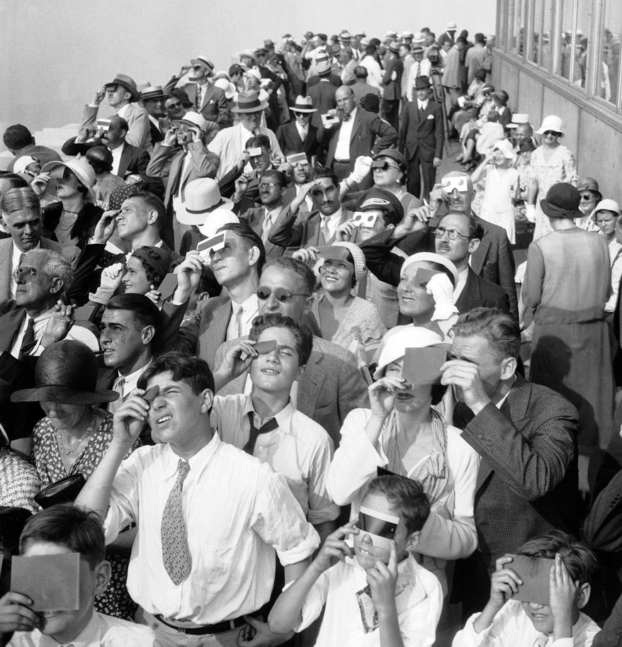 FILE - In this Aug. 31, 1932, file photo, eclipse watchers squint through protective film as they view a partial eclipse of the sun from the top deck of New York's Empire State Building in New York. Destinations are hosting festivals, hotels are selling out and travelers are planning trips for the total solar eclipse that will be visible coast to coast on Aug. 21, 2017. A narrow path of the United States 60 to 70 miles wide from Oregon to South Carolina will experience total darkness, also known as totality. (AP Photo, File)