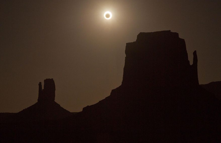 FILE - In this May 20, 2012, file photo, the new moon crosses in front of the sun creating an annular eclipse over West Mitten, left, and East Mitten buttes in Monument Valley, Ariz. Destinations are hosting festivals, hotels are selling out and travelers are planning trips for the total solar eclipse that will be visible coast to coast on Aug. 21, 2017. A narrow path of the United States 60 to 70 miles wide from Oregon to South Carolina will experience total darkness, also known as totality. (AP Photo/Julie Jacobson, File)