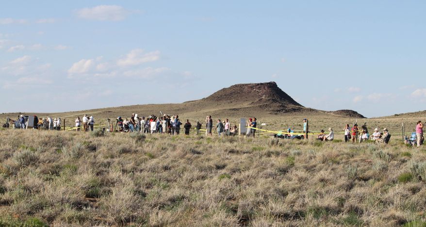 FILE - In this May 20, 2012, file photo, some 250 people line the fence line at the Petroglyph National Monument near Albuquerque, N.M., to watch the annular solar eclipse. Destinations are hosting festivals, hotels are selling out and travelers are planning trips for the total solar eclipse that will be visible coast to coast on Aug. 21, 2017. A narrow path of the United States 60 to 70 miles wide from Oregon to South Carolina will experience total darkness, also known as totality. (AP Photo/Susan Montoya Bryan, File)