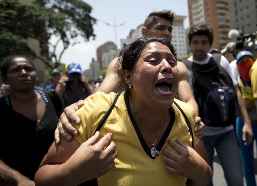 A woman cries in front of Venezuelan National Police line during clashes in Caracas, Venezuela, Tuesday, April 4, 2017. The demonstrators were trying to accompany opposition lawmakers in a march to the National Assembly for a session where they planned to debate removing Supreme Court magistrates who issued a ruling last week removing the last vestiges of power from the opposition-controlled congress. (AP Photo/Ariana Cubillos)