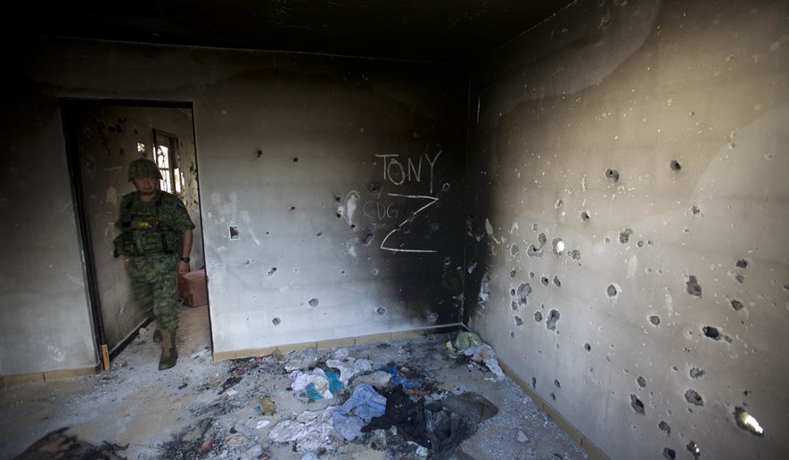 A soldier enters a bullet-riddled home, tagged with the initials CDG for the Gulf Cartel, and Z for Zetas, in Ciudad Victoria, in Mexico's state of Tamaulipas on Sept. 6, 2014. (Associated Press) **FILE**