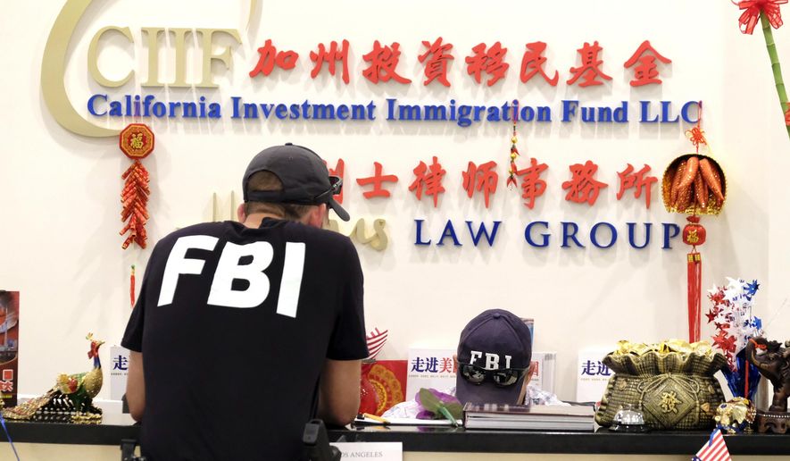Federal agents are seen inside California Investment Immigration Fund in San Gabriel, Calif., Wednesday, April 5, 2017. Federal authorities on Wednesday raided the Los Angeles-area business they say cheated a U.S. government visa program to obtain green cards for wealthy Chinese investors. (AP Photo/Rich Vogel