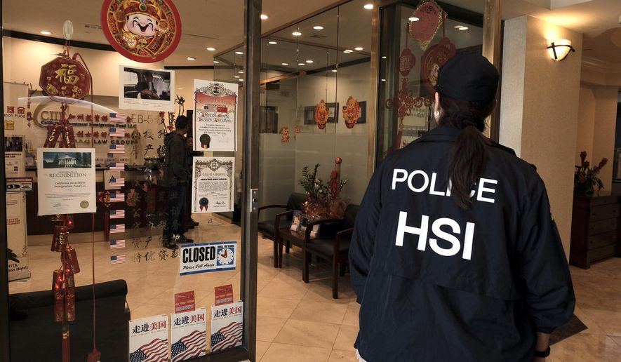 A police officer enters California Investment Immigration Fund in San Gabriel, Calif., Wednesday, April 5, 2017. Federal authorities on Wednesday raided the Los Angeles-area business they say cheated a U.S. government visa program to obtain green cards for wealthy Chinese investors. (AP Photo/Rich Vogel