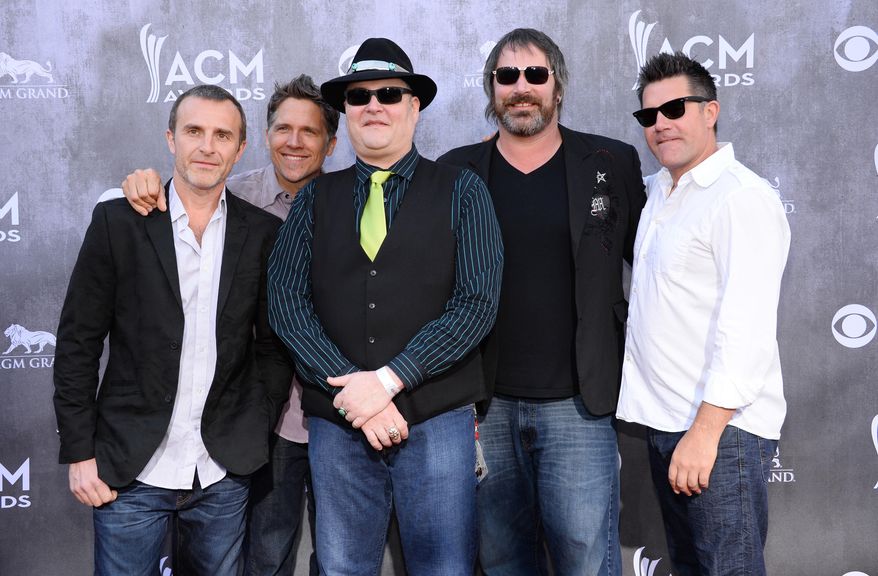 FILE- In this April 6, 2014, file photo, the musical group Blues Traveler arrives at the 49th annual Academy of Country Music Awards at the MGM Grand Garden Arena in Las Vegas. Blues Traveler is postponing their tour because front man John Popper needs medical attention. The band announced Friday, Aug. 5, 2016, that several concerts have been canceled or other bands would fill in for them because Popper must undergo surgery. (Photo by Al Powers/Powers Imagery/Invision/AP, File)