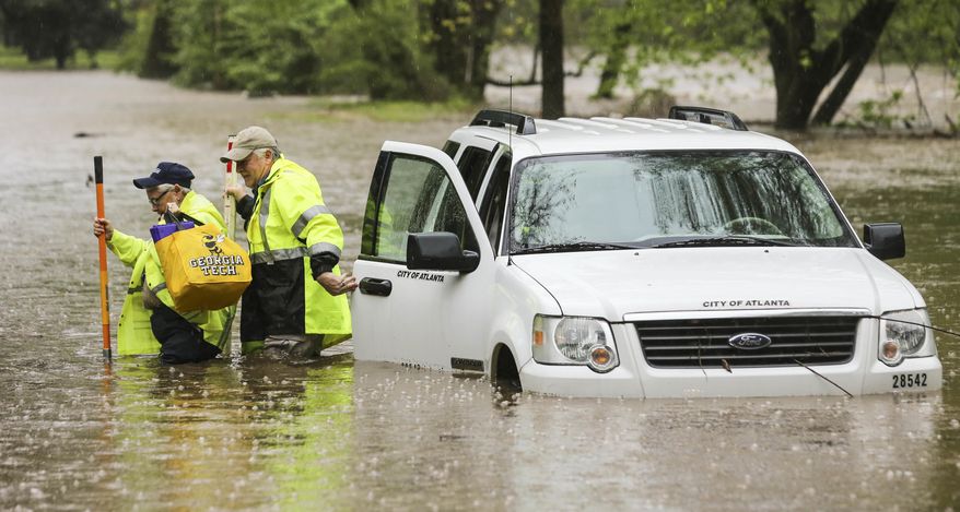 An Atlanta Watershed Management crew got caught in the Peachtree Creek overflow onto the flooded Woodward Way as they were accessing the flooded street in Atlanta, Wednesday, April 5, 2017. Severe storms raking the Southeast unleashed one large tornado and more than a half dozen apparent twisters Wednesday, toppling trees, roughing up South Carolina's 'peach capital' and raining out golfers warming up for the Masters. (John Spink/Atlanta Journal-Constitution via AP)