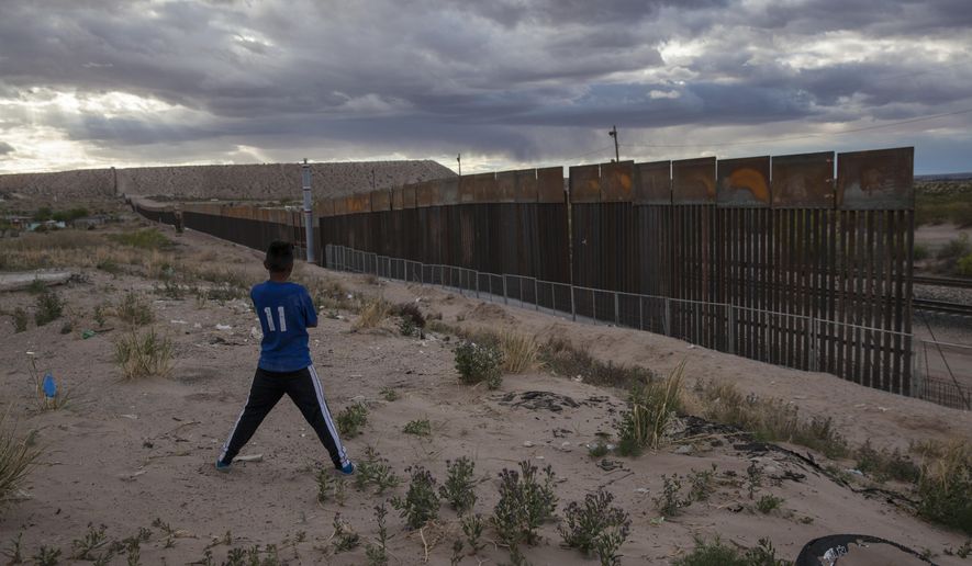 In this March 29, 2017, file photo, a youth looks at a new, taller fence being built along U.S.-Mexico border, replacing the shorter, gray metal fence in front of it, in the Anapra neighborhood of Ciudad Juarez, Mexico, across the border from Sunland Park, New Mexico. Most Americans oppose funding President Donald Trump&#39;s wall along the U.S.-Mexico border. That’s according to a poll released Thursday by The Associated Press-NORC Center for Public Affairs Research. (AP Photo/Rodrigo Abd, File)