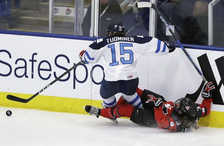 Finland defender Minttu Tuominen (15) and Canada defender Jocelyne Larocque (3) become entangled during the third period of a women&#x27;s ice hockey world championships semifinal, Thursday, April 6, 2017, in Plymouth, Mich. (AP Photo/Carlos Osorio)