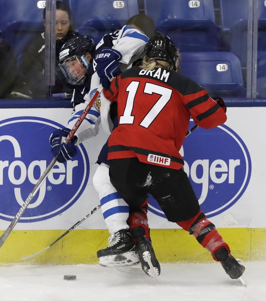 Canada forward Bailey Bram (17) checks Finland forward Riikka Valila during the third period of a semifinal in the women&#x27;s ice hockey world championships, Thursday, April 6, 2017, in Plymouth, Mich. (AP Photo/Carlos Osorio)