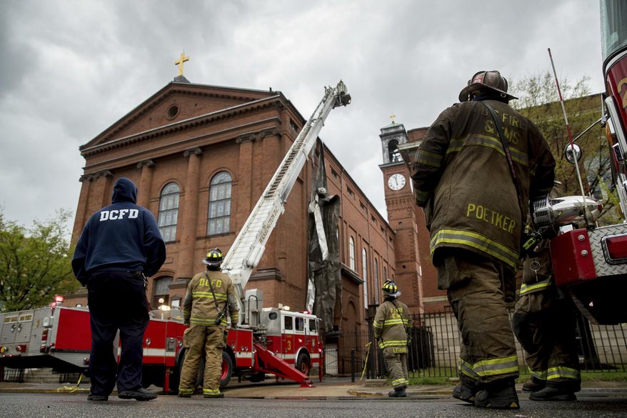 Firefighters work to cut pieces of damaged tin roof down after high winds damaged the roof of St. Aloysius Catholic Church at Gonzaga High School in Washington, Thursday, April 6, 2017. (AP Photo/Andrew Harnik)