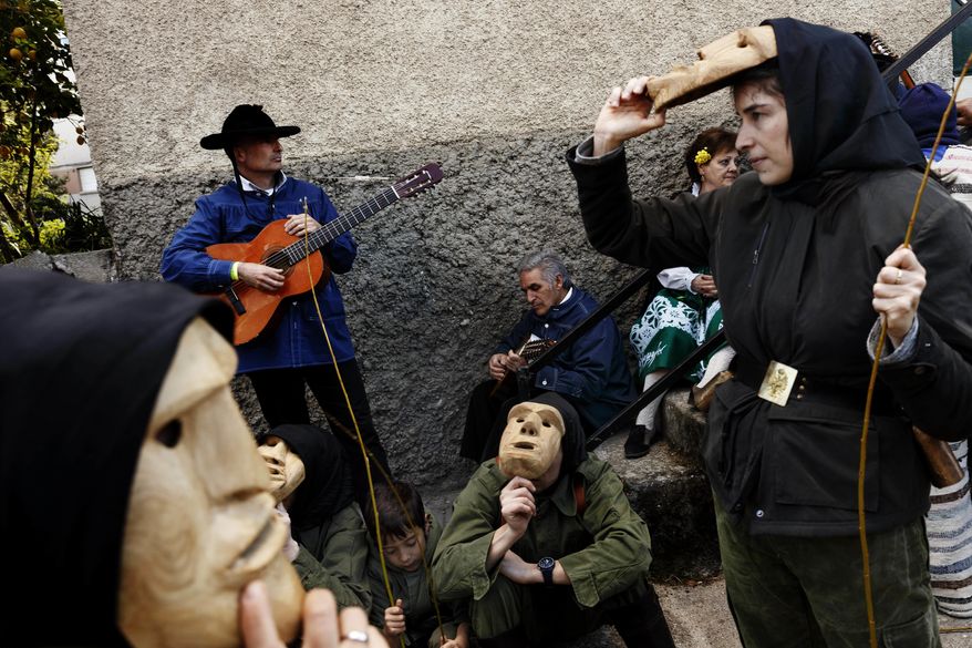 In this April 1, 2017 picture revelers from San Pedro Bernardo village wearing the traditional 'Machurrero' mask and outfit rest after a parade during a gathering of different villages' carnival masks and characters in the small village of Casavieja, Spain, Monday, April 3, 2017. (AP Photo/Daniel Ochoa de Olza)
