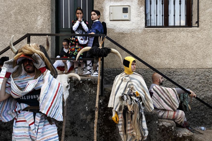In this April 1, 2017 picture revelers from Navalosa village wearing the traditional 'Cucurrumacho' mask and outfit rest after a parade during a gathering of different villages' carnival masks and characters in the small village of Casavieja, Spain, Monday, April 3, 2017. (AP Photo/Daniel Ochoa de Olza)