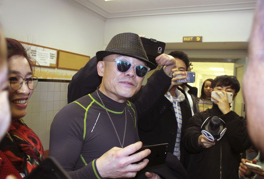 Chinese comedian Zhou Libo, center, is surrounded by reporters from Chinese media outlets, center, as he arrives with his wife Hu Jie, left, to court in Mineola, N.Y., on Long Island where Zhou pleaded not guilty to drug and weapon charges. The comedian and former judge on the "China's Got Talent" television program was arrested during a traffic stop Jan. 19 in Lattingtown, east of New York City. Police said he had been driving erratically and when they stopped him said they noticed a shoulder holster in the back seat and found a loaded pistol and two plastic bags containing crack cocaine in a backpack. (AP Photo/Frank Eltman)