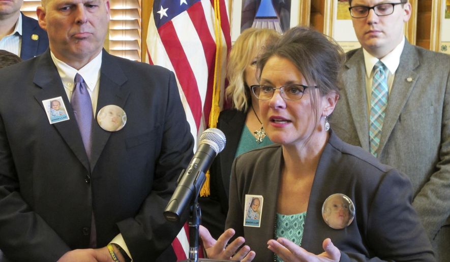 Sheryl Crosier, of St. Louis, speaks during a ceremony for Kansas Gov. Sam Brownback's signing of legislation aimed at giving parents more control over medical decisions for their disabled or critically ill children as her husband, Scott, watches to her left, Friday, April 7, 2017, at the Statehouse in Topeka, Kan. The measure is called "Simon's Law" for the Crosiers' 3-month-old son who died in 2010. (AP Photo/John Hanna)
