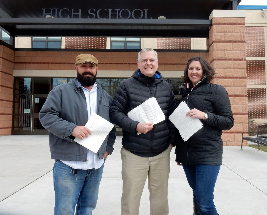 In this March 2017 photo, Fred Stauffer, center, a former Unionville High School teacher, is flanked by former students Dan Fogel and Megan Plunkett Cromer at the school in Kennett Square, Pa. As part of a class assignment back in the early 90s, Stauffer had his classes write what they thought they would be in the future. Those letters were revealed 24 years later. (Fran Maye /Delaware County Daily Times via AP)