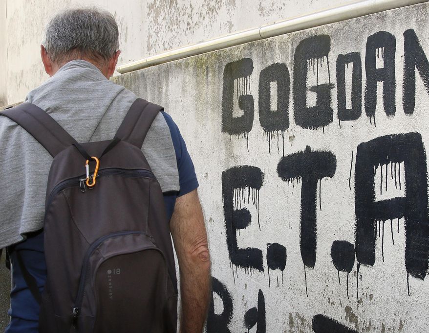 A man walks past graffiti reading "ETA , Basque country and Freedom", in Sare, southwestern France, Friday, April 7, 2017. The armed Basque separatist group ETA, inactive for more than five years, is to hand over its arms Saturday, a finishing touch to a 43-year violent campaign that claimed 829 lives, mostly in Spain. (AP Photo/Bob Edme)