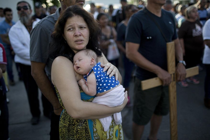 In this Friday, March 24, 2017 photo, Cuban Elaide Vilchez carries her one-month-old daughter Emily Melania Garcia during a religious procession adapted to reflect the plight of immigrants, in Nuevo Laredo, Mexico, across the border from Laredo, Texas. (AP Photo/Rodrigo Abd)