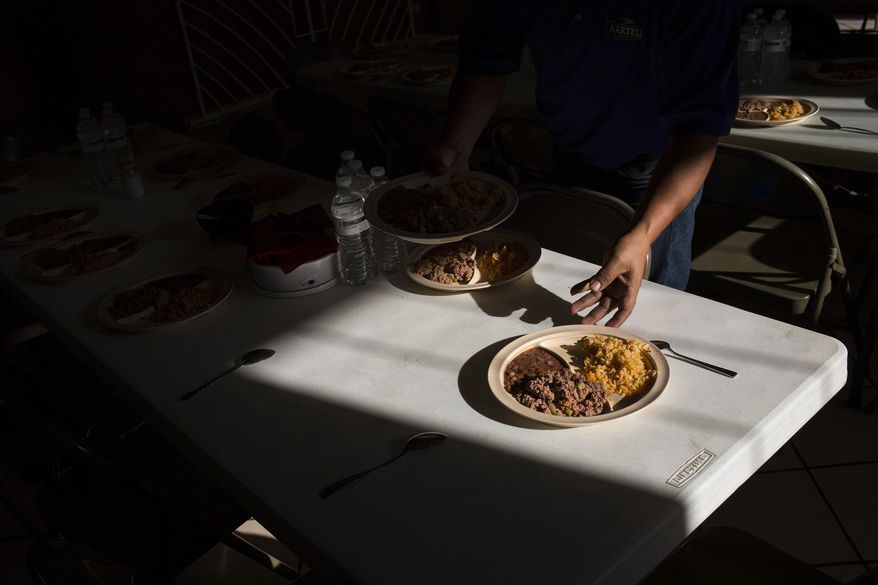 In this Saturday, March 25, 2017 photo, a Cuban migrant reaches for a plate of rice and beans at the migrant shelter "Casa del Migrante" in Nuevo Laredo, Mexico, across the border from Laredo, Texas. (AP Photo/Rodrigo Abd)