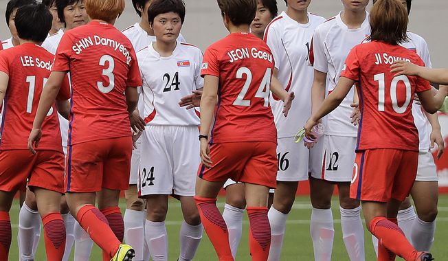 South Korean, in red uniforms, and North Korean women soccer players hi-five after their AFC Women's Asian Cup Jordan 2018 qualifying soccer match at the Kim Il Sung Stadium on Friday, April 7, 2017, in Pyongyang, North Korea. South Korea equalized the score to 1-1 at the end of the match. (AP Photo/Jon Chol Jin)