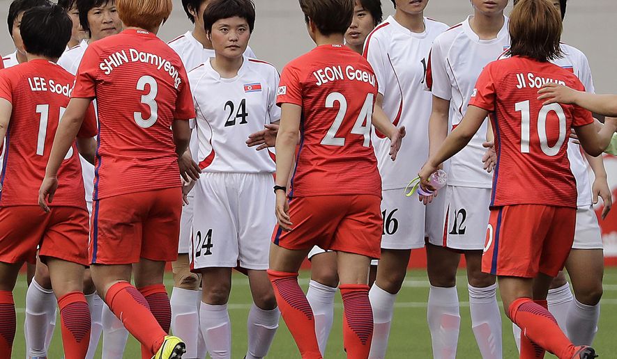 South Korean, in red uniforms, and North Korean women soccer players hi-five after their AFC Women's Asian Cup Jordan 2018 qualifying soccer match at the Kim Il Sung Stadium on Friday, April 7, 2017, in Pyongyang, North Korea. South Korea equalized the score to 1-1 at the end of the match. (AP Photo/Jon Chol Jin)