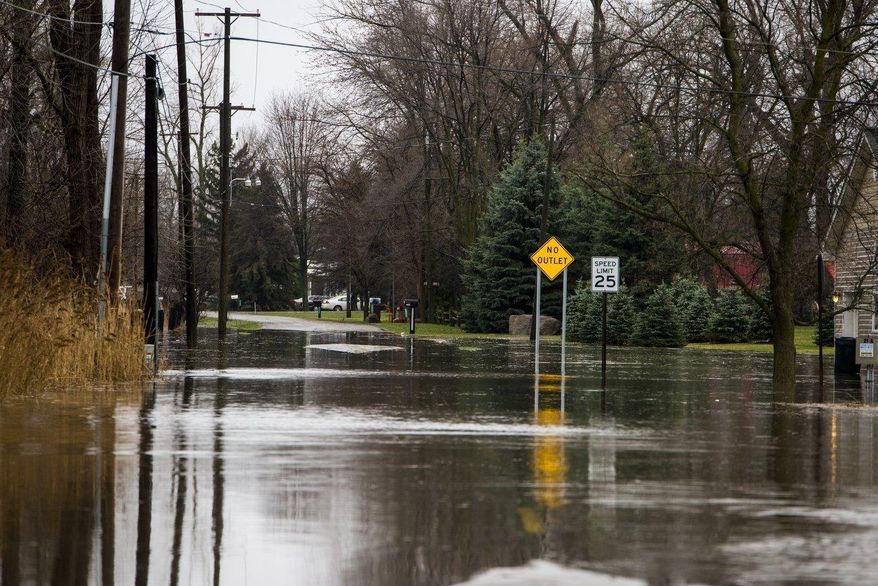 A street is flooded on Evergreen Drive on Middlegrounds Island, Mich., is flooded by the Saginaw River on Thursday, April 6, 2017. A mix of snow and rain across much of Michigan is causing hazardous driving conditions and bringing the threat of flooding in places. (Tori Schneider/The Bay City Times via AP)