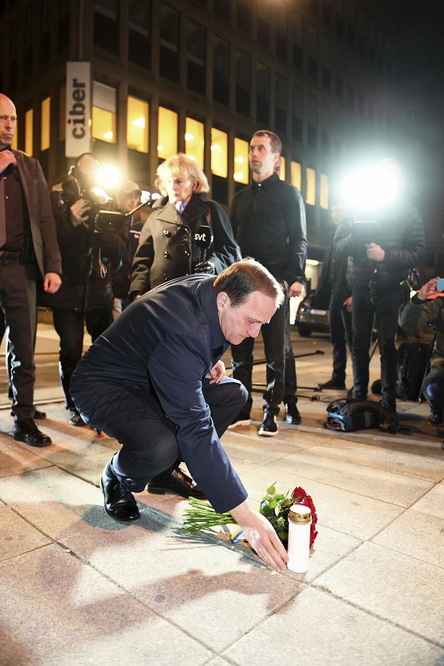 Sweden's Prime Minister Stefan Lofven places flowers and a candle on Queens Street where a hijacked beer truck ploughed into pedestrians at a central Stockholm department store Friday. Lofven laid a bouquet of red roses and lit a candle near the department store in Stockholm where a hijacked beer truck crashed on a busy shopping street. (Fredrik Sandberg / TT via AP)