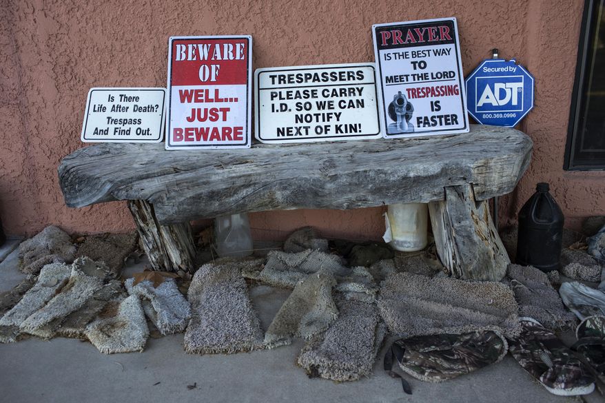 In this Sunday, April 2, 2017 photo, signs warning trespassers line a wooden bench surrounded by makeshift slip-ons known as "carpet shoes" on the porch of rancher Jim Chilton, in Arivaca, Ariz.. Hilton, who finds the slip-ons abandoned on his property, says they are worn by people illegally crossing the border as a way to keep authorities from finding their tracks. (AP Photo/Rodrigo Abd)