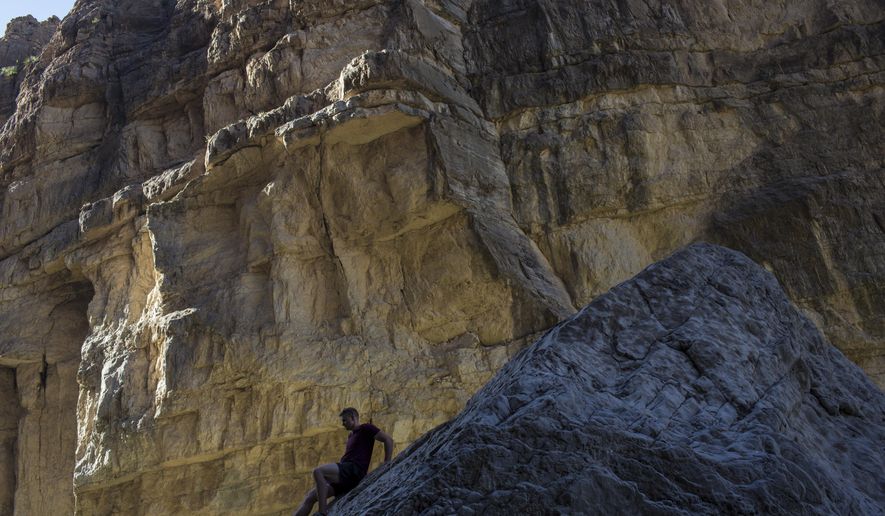In this Monday, March 27, 2017 photo, a man descends a rock on the bank of the Rio Grande, just a few feet from a cliff wall that is Mexico, in Santa Elena Canyon, at Big Bend National Park in Texas. (AP Photo/Rodrigo Abd)