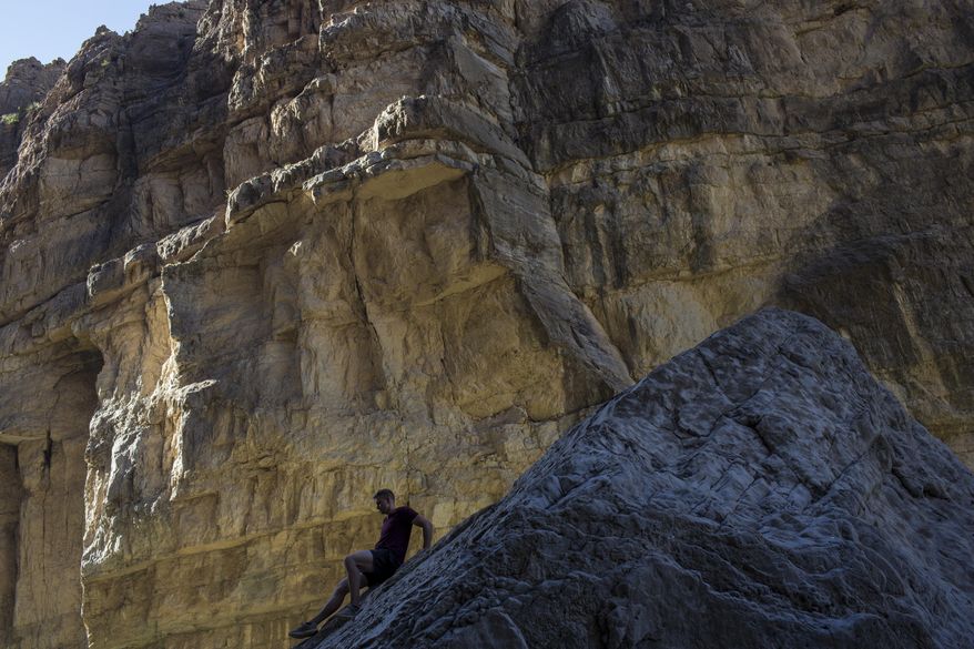 In this Monday, March 27, 2017 photo, a man descends a rock on the bank of the Rio Grande, just a few feet from a cliff wall that is Mexico, in Santa Elena Canyon, at Big Bend National Park in Texas. (AP Photo/Rodrigo Abd)