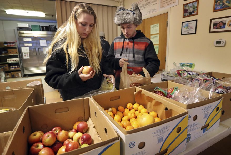 In this Monday, March 27, 2017 photo Sunny Larson, left, and Zak McCutcheon pick produce while gathering provisions to take home at the Augusta Food Bank in Augusta, Maine. Republican Gov. Paul LePage says his call to ban the use of food stamps for soda and candy is backed by science and a desire to reduce obesity and diabetes in the nation's oldest state. (AP Photo/Robert F. Bukaty)
