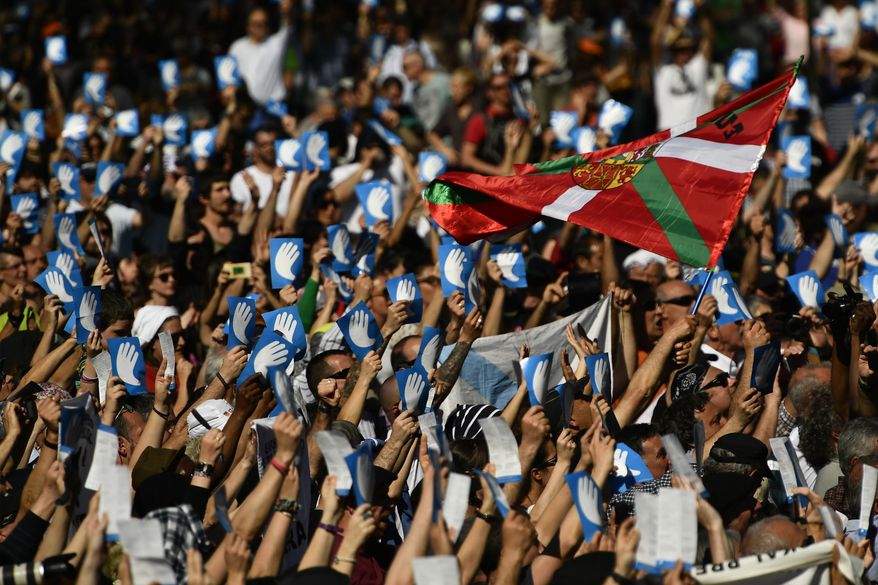 Pro independence Basque followers hold up the symbol of the day called ''Artisans of the Peace'' close to a Basque flag during a meeting after the announcement that ETA handed over its arms in Bayonne, southwestern France, Saturday, April 8, 2017. The Basque separatist group ETA, inactive for more than five years, handed over its arms Saturday, putting a finishing touch to a 43-year violent campaign that claimed the lives of over 800 people mostly in Spain. (AP Photo/Alvaro Barrientos)