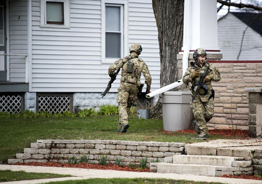 In this Thursday, April 6, 2017 photo, FBI agents pass through a resident's front lawn while searching for Joseph Jakubowski, in Janesville, Wis. A manhunt was underway Friday for Jakubowski, suspected of stealing firearms from a southern Wisconsin gun store, threatening an unspecified attack that prompted several schools to close, and sending an anti-government manifesto to President Donald Trump. (Angela Major/The Janesville Gazette via AP)
