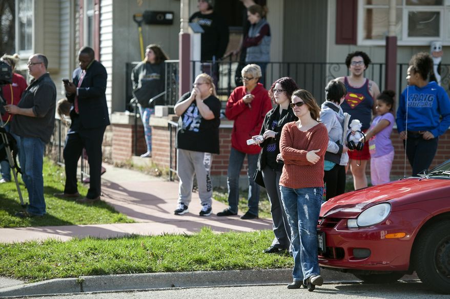 Residents gather on Eisenhower Avenue as authorities searched what appeared to be a vacant home, Friday, April 7, 2017, in Janesville, Wis. A manhunt was underway Friday for a man suspected of stealing firearms from a southern Wisconsin gun store, threatening an unspecified attack that prompted several schools to close, and sending an anti-government manifesto to President Donald Trump. (Angela Major/The Janesville Gazette via AP)