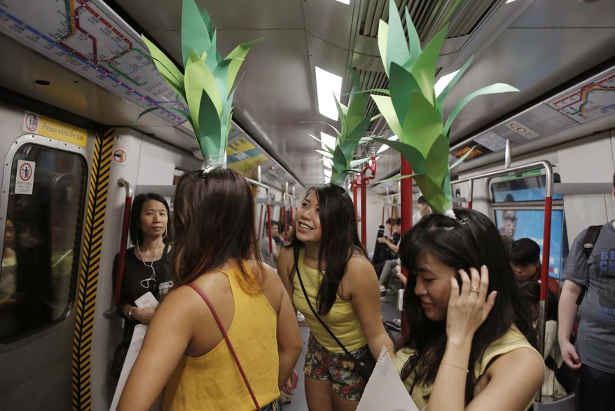 Rugby fans dressed as pineapples ride on a train as they head to the Hong Kong Rugby Sevens in Hong Kong, Saturday, April 8, 2017. (AP Photo/Kin Cheung)