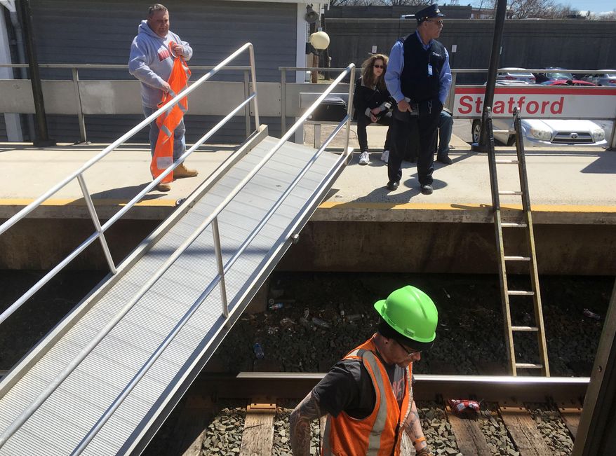 Metro North Railroad employees tend to a temporary passenger walkway after it fell from the platform at the Stratford train station in Stratford, Conn., on Saturday, April 8, 2017. Witnesses said a woman appeared to have suffered an injury to her hand as the temporary bridge collapsed while she was walking on it. (AP Photo/Ron Blum)