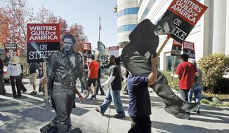 FILE - In this Nov. 26, 2007 file photo, striking writers carry live sized photos of legendary actors, Marlon Brando, left, and James Dean to express their support to members of the Writers Guild of America (WGA), outside the Raleigh Studios in Los Angeles. On Monday, April 10, 2017, the Writers Guild of America will pick up negotiations again with the Alliance of Motion Pictures and Television Producers, which represents broadcast networks and movie studios, over a new contract. The WGA is moving to authorize a strike, but Hollywood is hoping to avoid a work stoppage like the 100-day strike of 2007.  (AP Photo/Damian Dovarganes, File)
