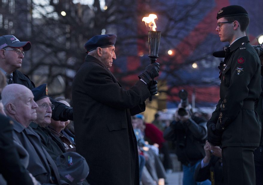 A veteran holds a torch of remembrance during a vigil at the National War Memorial to commemorate the 100th anniversary of the Battle of Vimy Ridge in Ottawa, Ontario, Saturday, April 8, 2017. (Justin Tang/The Canadian Press via AP)