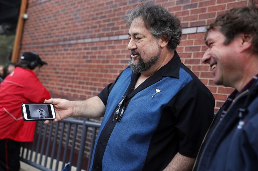 Alan Bozich, left, holds up his phone to watch a video of Chuck Berry as he stands in line with Jimmy Herrmann, right, to pay their respects to the rock 'n' roll legend during Berry's public viewing Sunday, April 9, 2017, in St. Louis. The man behind such classics as "Johnny B. Goode," ''Sweet Little Sixteen" and "Roll Over Beethoven" died on March 18 at the age of 90. (AP Photo/Jeff Roberson)