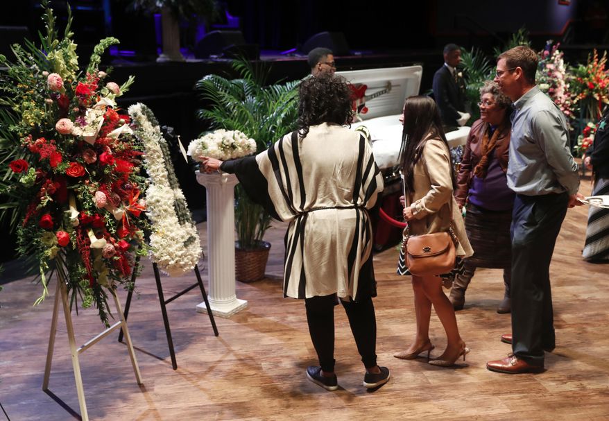 Fans look at a flower arrangement in the shape of a guitar sent by members of the Rolling Stones during a public viewing for rock 'n' roll legend Chuck Berry Sunday, April 9, 2017, in St. Louis. The man behind such classics as "Johnny B. Goode," ''Sweet Little Sixteen" and "Roll Over Beethoven" died on March 18 at the age of 90. (AP Photo/Jeff Roberson)