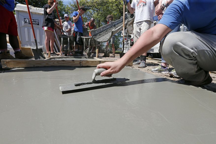In this Thursday, March 23, 2017 photo, faculty and students from Northwestern University and the University of Illinois work on a home in the Lower 9th Ward that was being built by Habitat for Humanity, in New Orleans. A major rebuilding project is set to bring hundreds of new residents into the neighborhood, in what developers, officials and some residents hope will mark an important turning point. But others have concerns about the new development and whether it's the right fit for the historic, African-American neighborhood. (AP Photo/Gerald Herbert)