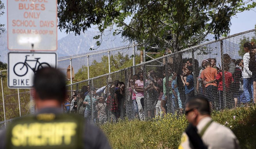 Students from North Park Elementary School in San Bernardino, Calif., line the fence after multiple law enforcement agencies responded to a fatal shooting at the school, Monday, April 10, 2017. (Rick Sforza/Los Angeles Daily News via AP)
