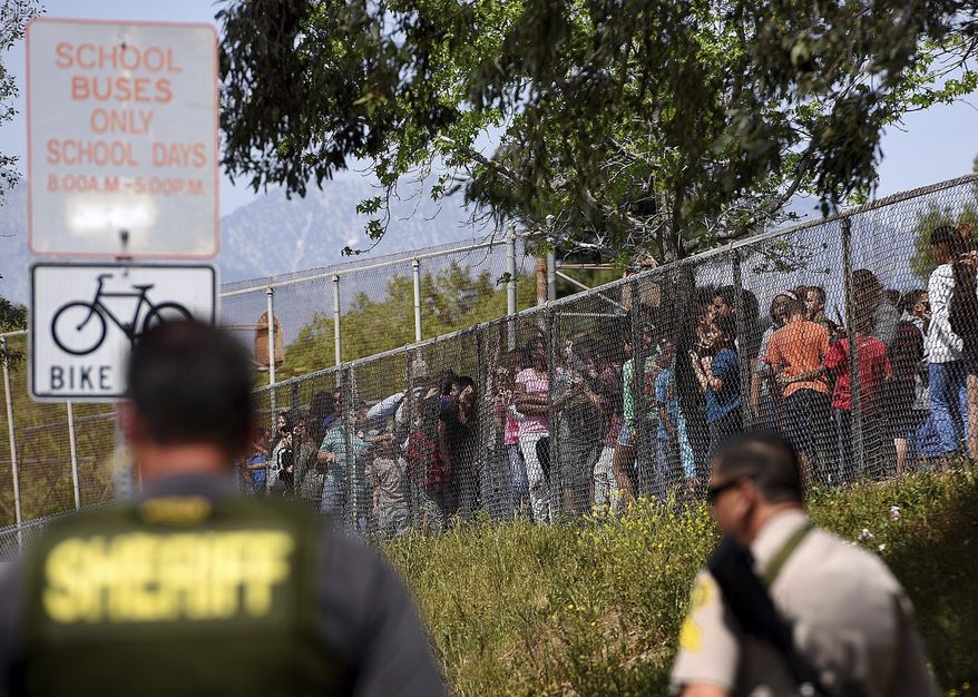 Students from North Park Elementary School in San Bernardino, Calif., line the fence after multiple law enforcement agencies responded to a fatal shooting at the school, Monday, April 10, 2017. (Rick Sforza/Los Angeles Daily News via AP)