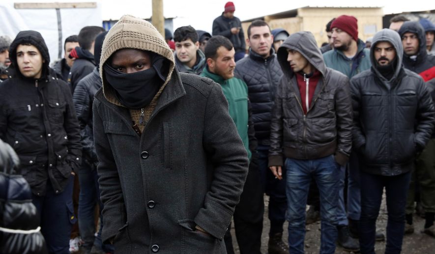 Migrants watch French officials tour a makeshift camp set outside Calais, France, Tuesday Feb. 23, 2016. People fleeing conflict and poverty in Africa, the Mideast and Asia are facing an evening deadline to move out of the camp in the French port of Calais that has become a flashpoint in Europe's migrant crisis. (AP Photo/Jerome Delay)
