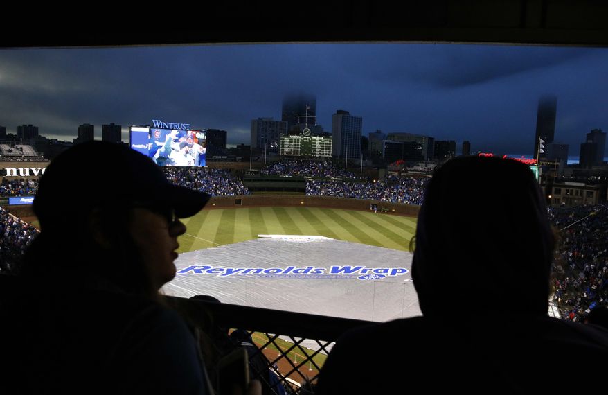 Baseball fans wait out a rain delay during a baseball game between the Chicago Cubs and the Los Angeles Dodgers on home opening day, Monday, April 10, 2017, in Chicago. (AP Photo/Nam Y. Huh)