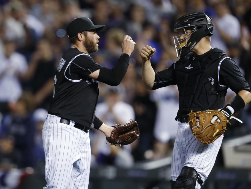Colorado Rockies relief pitcher Greg Holland, left, is congratulated by catcher Dustin Garneau after getting Los Angeles Dodgers' Chase Utley to ground out to end a baseball game Saturday, April 8, 2017, in Denver. The Rockies won 4-2. (AP Photo/David Zalubowski)