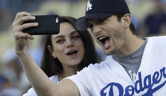 FILE- In this Oct. 19, 2016, file photo, Ashton Kutcher and wife Mila Kunis take a selfie before Game 4 of the National League baseball championship series between the Chicago Cubs and the Los Angeles Dodgers in Los Angeles. Kutcher offered emotional praise for his wife Mila Kunis, his twin brother and the rest of his family in accepting an award for character in his native Iowa on April 9, 2017. (AP Photo/David J. Phillip, File)