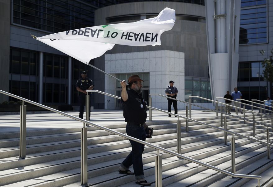 David Zion Brugger waves a flag in support of defendants on trial at a federal courthouse, Monday, April 10, 2017, in Las Vegas. Protesters gathered outside the courthouse in support of six defendants accused of wielding weapons against federal agents during a 2014 standoff involving cattleman and states' rights advocate Cliven Bundy. (AP Photo/John Locher)