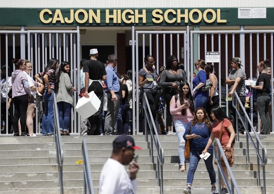 Parents and guardians of North Park Elementary School students wait at Cajon High School to pick up their children Monday, April 10, 2017, in San Bernardino, Calif. A deadly shooting occurred at the elementary school. (AP Photo/Jae C. Hong)