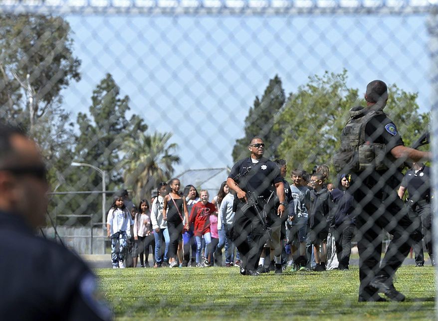 A San Bernardino police officer guides students on to the playground as multiple law enforcement agencies respond to a shooting at North Park Elementary school in San Bernardino, Calif., Monday, April 10, 2017. (Rick Sforza/Los Angeles Daily News via AP)
